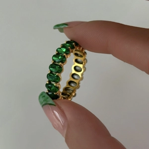 Macro view of gold plated eternity ring featuring oval cut emerald green zircon stones