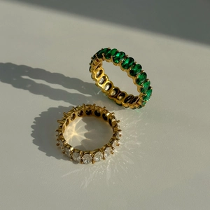 Detail of 18k gold plated eternity rings featuring emerald and clear zircon gemstones