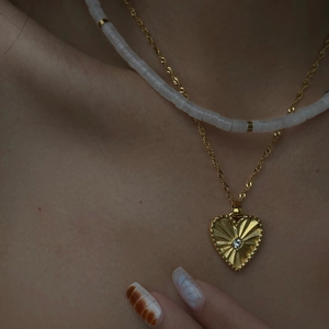 Detail of layered 18k gold plated heart pendant necklace with white beads on model