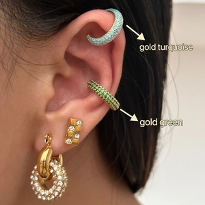 Κοντινό πλάνο με χρυσά ear cuffs με τιρκουάζ και πράσινα ζιργκόν στο αυτί ενός μοντέλου