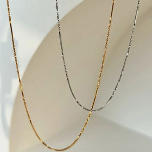 Detail of 18k gold and silver herringbone snake chain necklaces with metallic luster