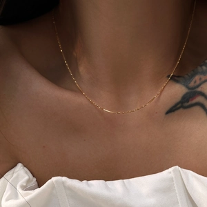 Close-up of 18k gold plated snake chain necklace worn on model for a layered look