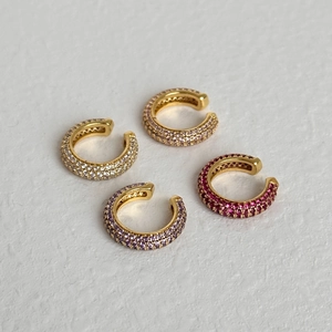 Λεπτομέρεια από τέσσερα χρυσά ear cuffs με πολύχρωμα ζιργκόν σε κοντινή λήψη macro