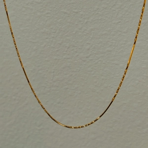 Close-up of 18k gold plated flat snake chain necklace with detailed woven texture
