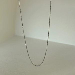 Close-up of fine silver-plated snake chain necklace with flat faceted texture finish