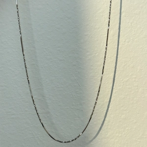 Macro detail of silver snake bone chain featuring a fine glitter texture and metallic glow
