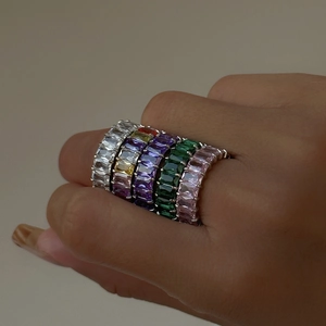 Detailed macro view of five 18k gold plated eternity rings with colorful baguette crystals