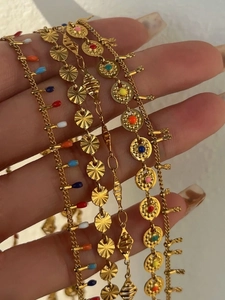 Detail van 18k vergulde kettingen met kleurrijke emaille hangers in de hand gehouden