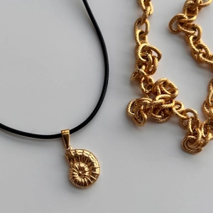 Makro-Detail des 18k vergoldeten Nautilus-Anhängers mit schwarzer Kordelkette