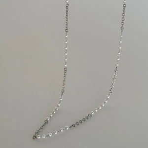 Detail view of 18k gold plated waist chain featuring white pearls and textured metal links