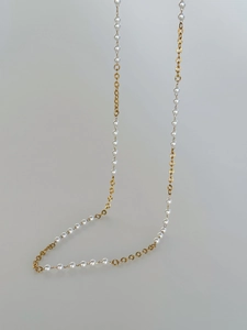 Detailed close-up of 18k gold plated textured metal rings and elegant pearl body chain