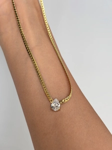 Detailed close-up of 18k gold-plated herringbone chain with a pear-cut zircon pendant