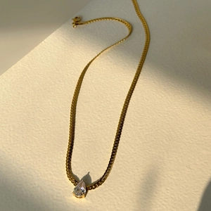 Elegant gold snake chain necklace featuring a sparkling teardrop zircon pendant