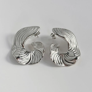 Détail macro de boucles d'oreilles argentées en acier titane avec motif de coquillage