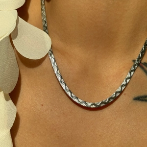 Close-up of a silver 4mm herringbone snake chain necklace on neck with textured finish