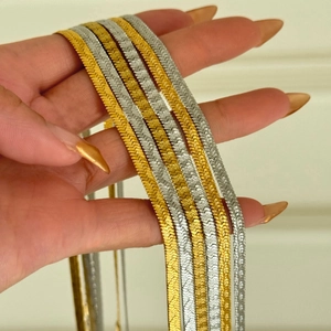 Close-up of 4mm 18k gold and silver flat snake bone chain necklaces held in hand
