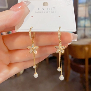 Detail of gold floral tassel earrings with sparkling cubic zirconia and white pearls
