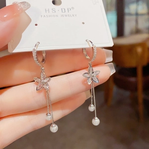 Detail of silver drop earrings with zircon flower petals and white pearl tassels