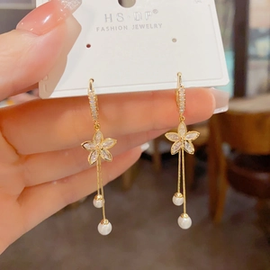 Detail of gold flower earrings with sparkling cubic zirconia and hanging pearl tassels