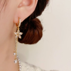 Detail of elegant gold tassel earrings with zircon flowers and pearls on model