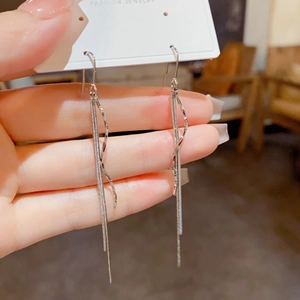 Detail van elegante zilveren golvende kwastjes oorbellen met lange fijne kettingen