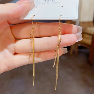 Detailopname van elegante lange gouden golf kwastje oorbellen met slangenkettingen