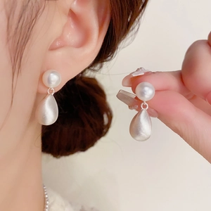 Detalle de pendientes de perlas de agua dulce y gota de plata mate en el modelo