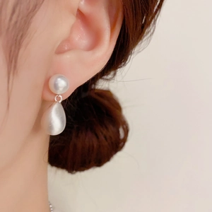 Detalle de pendiente de gota de perla de agua dulce en modelo con acabado plateado elegante