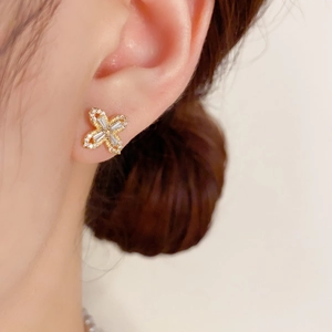 Sparkling gold four-leaf flower stud earrings with micro-pave crystals on a model