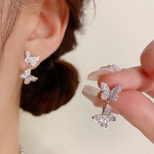 Macro detail of silver butterfly earrings with full diamond pavé settings and double drops