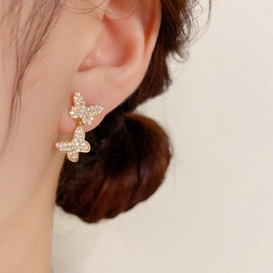 Elegant gold double butterfly earrings with sparkling crystals shown on a female model