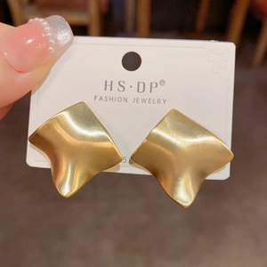 Detail of gold geometric brushed metal stud earrings with S925 silver needle on a card