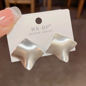 Macro shot of geometric brushed matte silver stud earrings on a card display