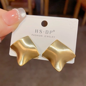 Detail shot of matte gold irregular geometric earrings with brushed metal texture