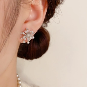 Elegante Schneeflocken-Ohrringe mit zarten Perlen und Zirkonia am Ohr eines weiblichen Models