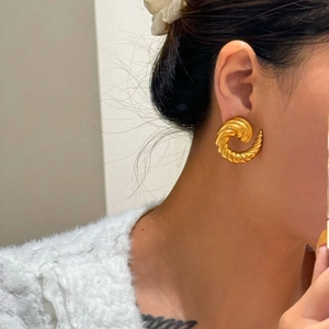 Macro shot of gold-plated spiral gypsy earrings with vintage textured surface