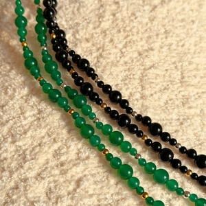 Macro detail of agate beaded necklace with green and black stones and gold spacers