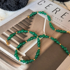 Detail of green beaded necklace with gold spacers on magazine, vintage style