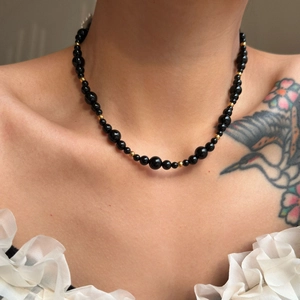 Close-up of black onyx bead necklace with gold spacers worn by model for retro style