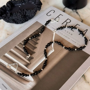Modern black bead necklace with silver metal accents laid on a lifestyle magazine