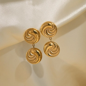 Detail von 18k vergoldeten Knopfohrringen mit Spiraltextur auf champagnerfarbenem Seidenstoff