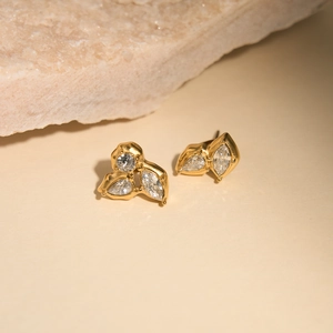 Macro shot of 18K gold plated stud earrings with zircons on natural stone background