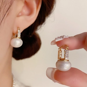 Detailed view of French style pearl hoop earrings with crystal pavé on golden settings
