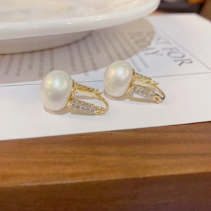 Detailed close-up of French-style pearl earrings with micro-pave crystals on gold plating