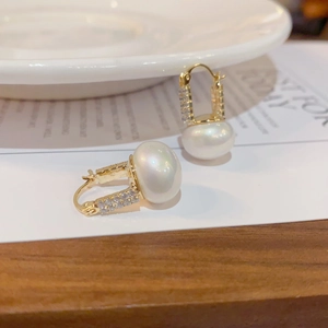 Macro shot of elegant gold earrings with micro-inlaid diamonds and lustrous white pearls