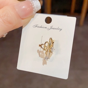Close-up of golden intertwined heart clip-on earrings with clear teardrop pendants