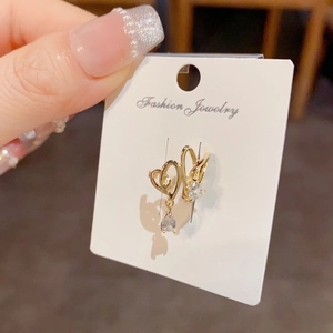 Detail of gold layered heart earrings with teardrop zircon on a white card