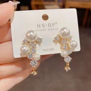 Détail des boucles d'oreilles en argent S925 avec perles blanches et pompons en zircon