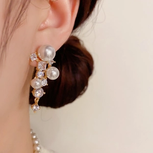 Gros plan de boucles d'oreilles à pampilles dorées avec perles blanches et zircons