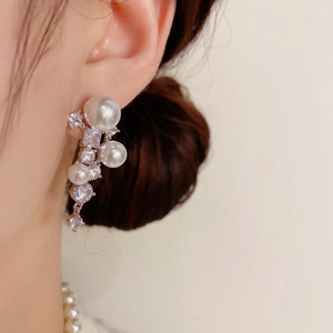 Détail de boucles d'oreilles pampilles en zircons et perles portées par un mannequin